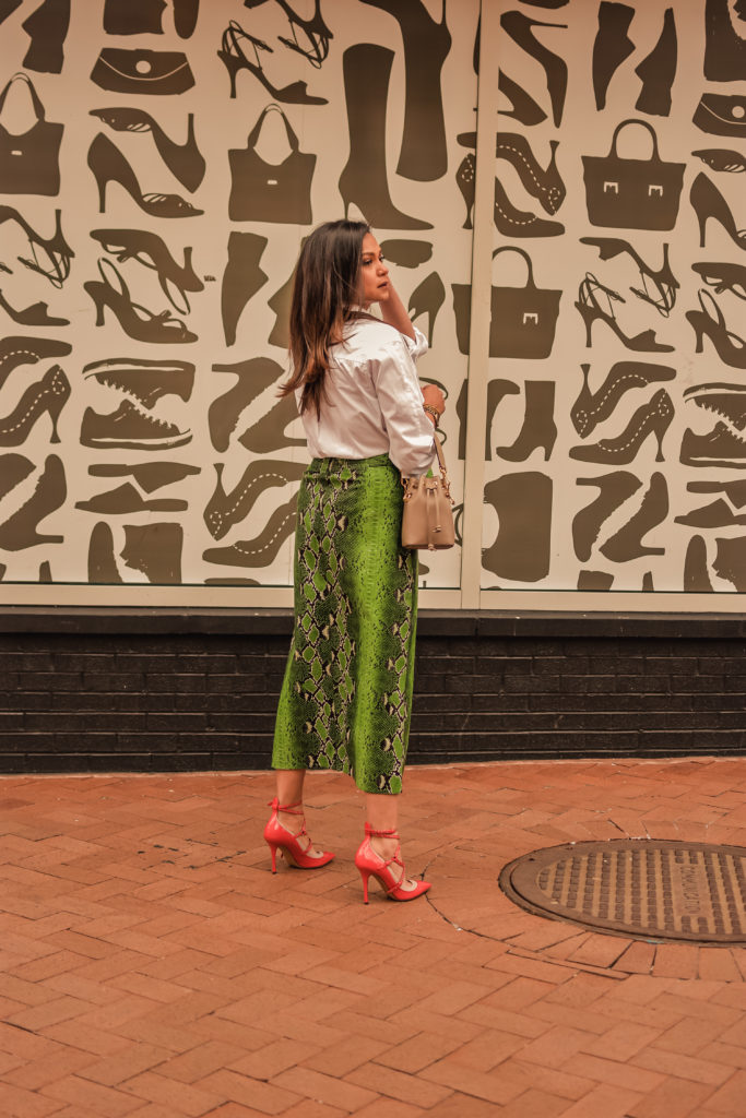 I am wearing a python print green leather skirt with a white blouse, citrus Valentino pumps and carrying a fendi bucket bag. Im talking about ways to transition your closet from winter to spring. myriad musings, saumya shiohare 