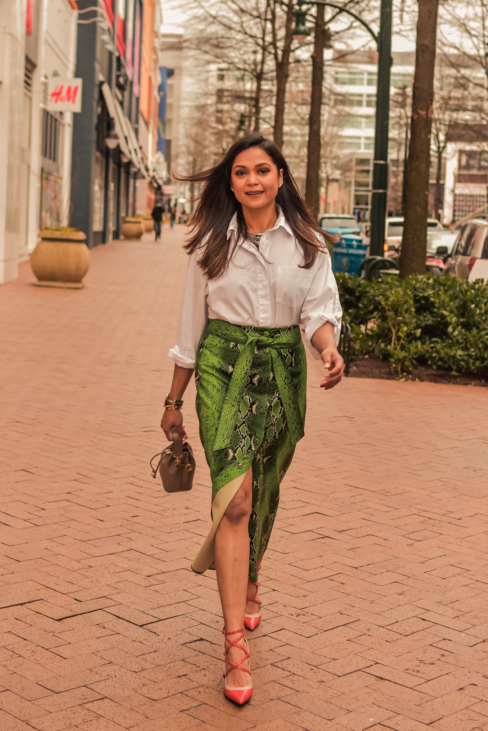 I am wearing a python print green leather skirt with a white blouse, citrus Valentino pumps and carrying a fendi bucket bag. Im talking about ways to transition your closet from winter to spring. myriad musings, saumya shiohare 